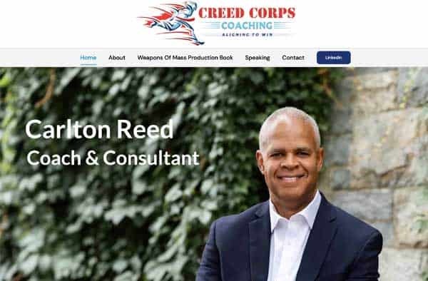 A smiling man in a suit sits outdoors in front of a stone wall and greenery. The website header reads “Creed Corps Coaching,” making this the perfect addition to any professional website portfolio. Text below says “Carlton Reed, Coach & Consultant.”.